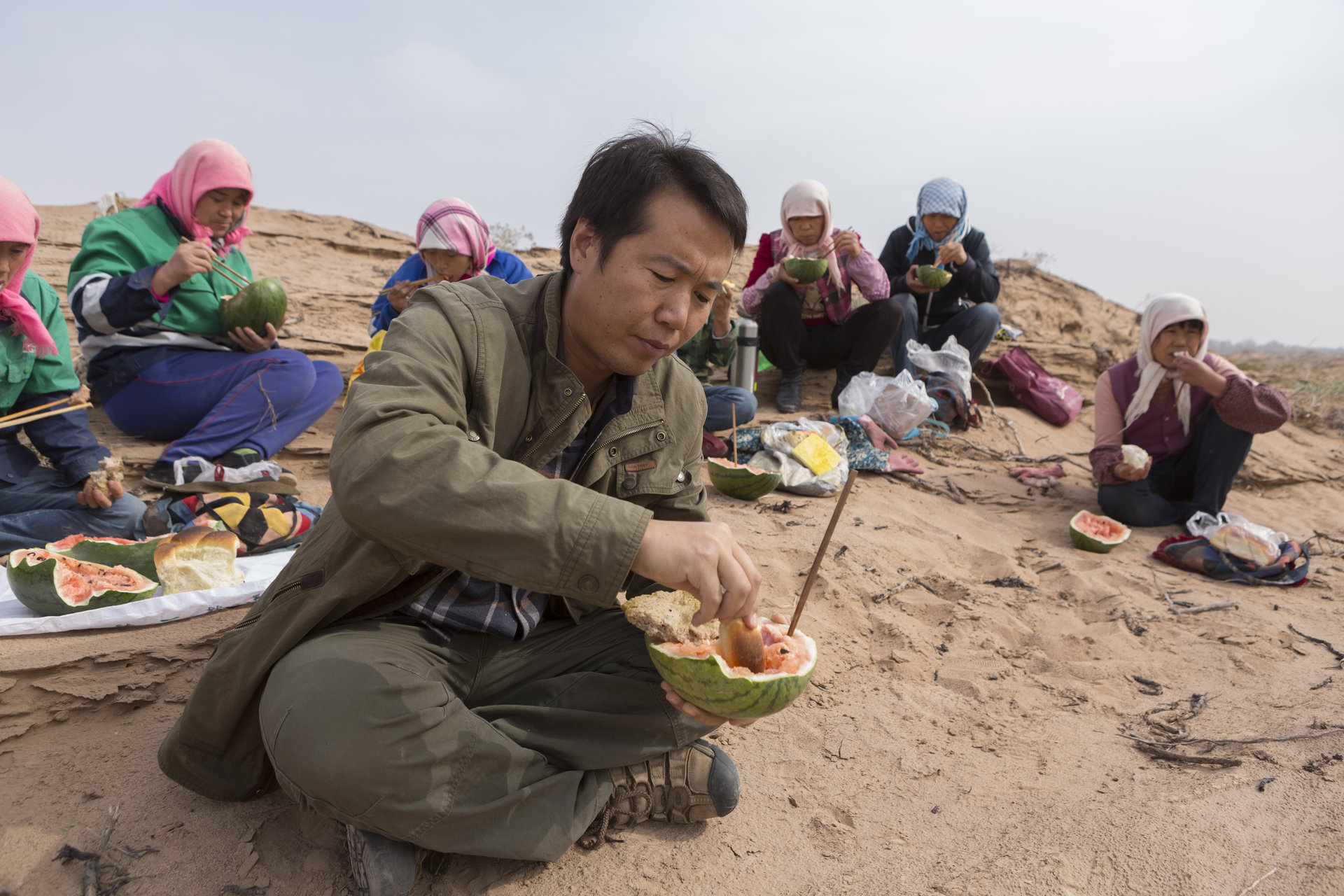 壓沙間隙，馬俊河和村民在沙丘上午飯“西瓜泡饃”