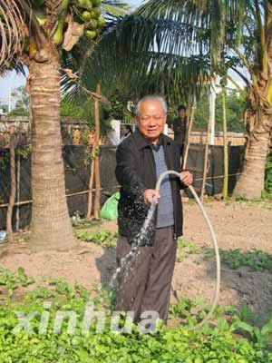 陳蘇厚在自家菜園澆菜