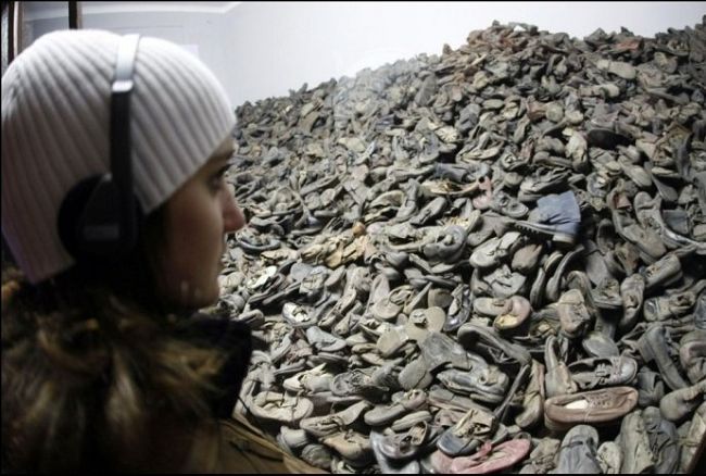 參觀者注視著堆積如山的遇難者的鞋子