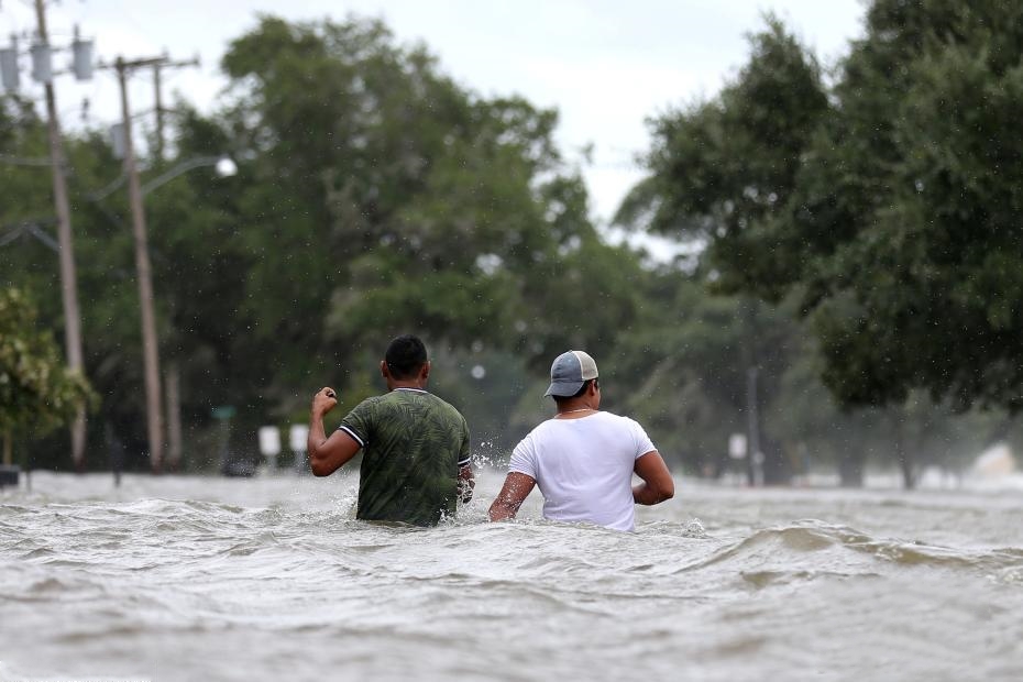 當地時間7月13日，人們艱難地穿過被洪水淹沒的街道